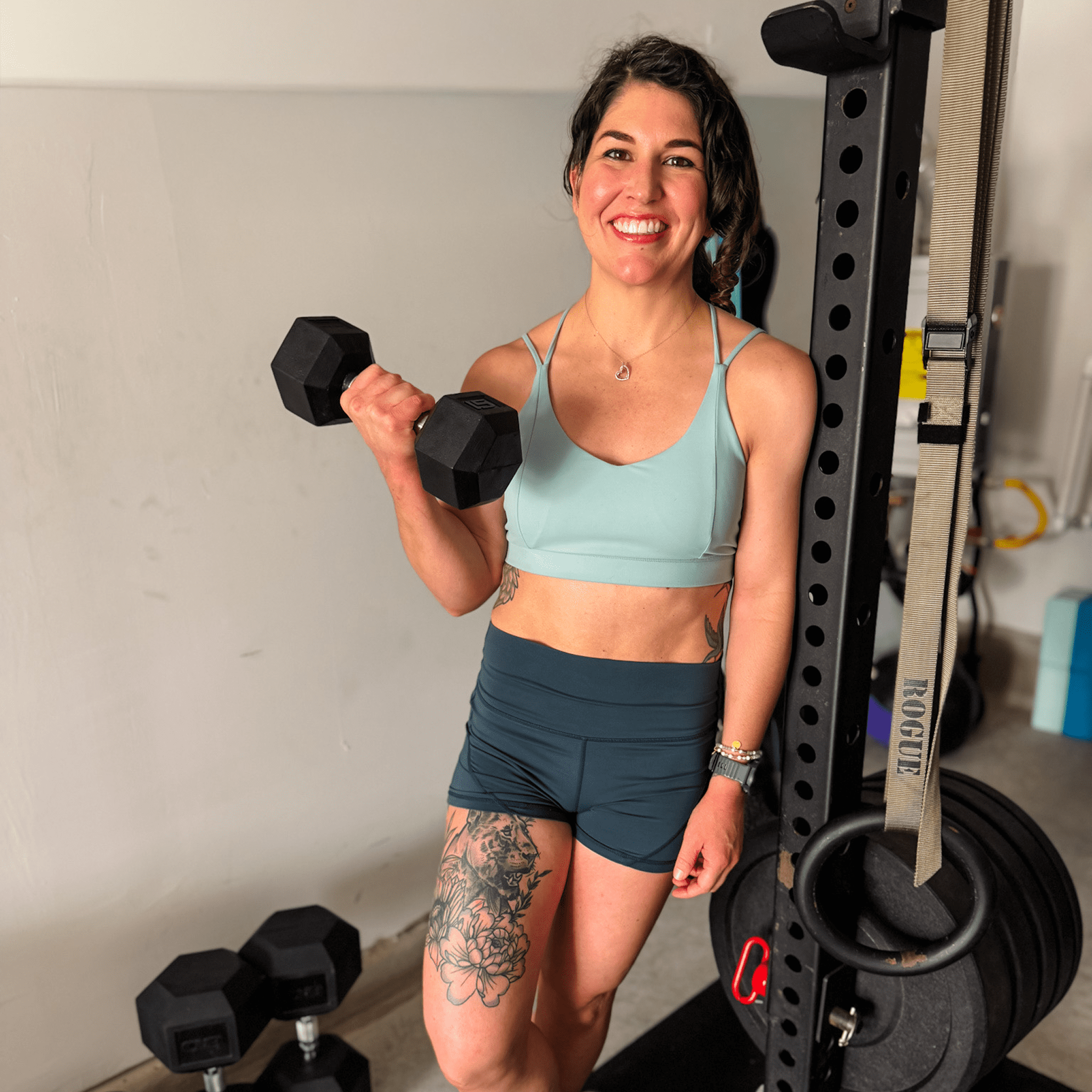 Woman smiling, holding dumbbell in gym.