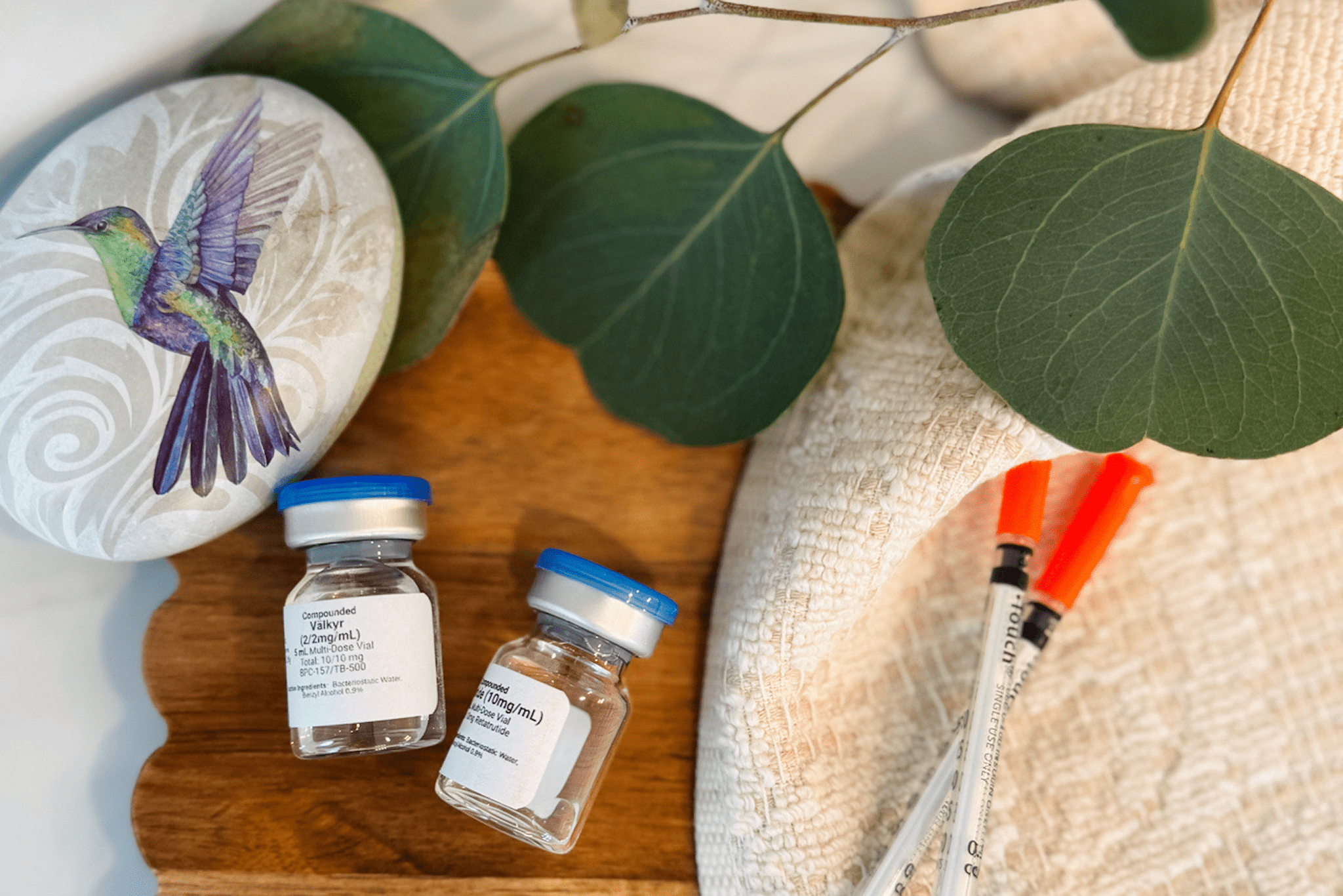 Vials and syringes on wooden surface, leaves.