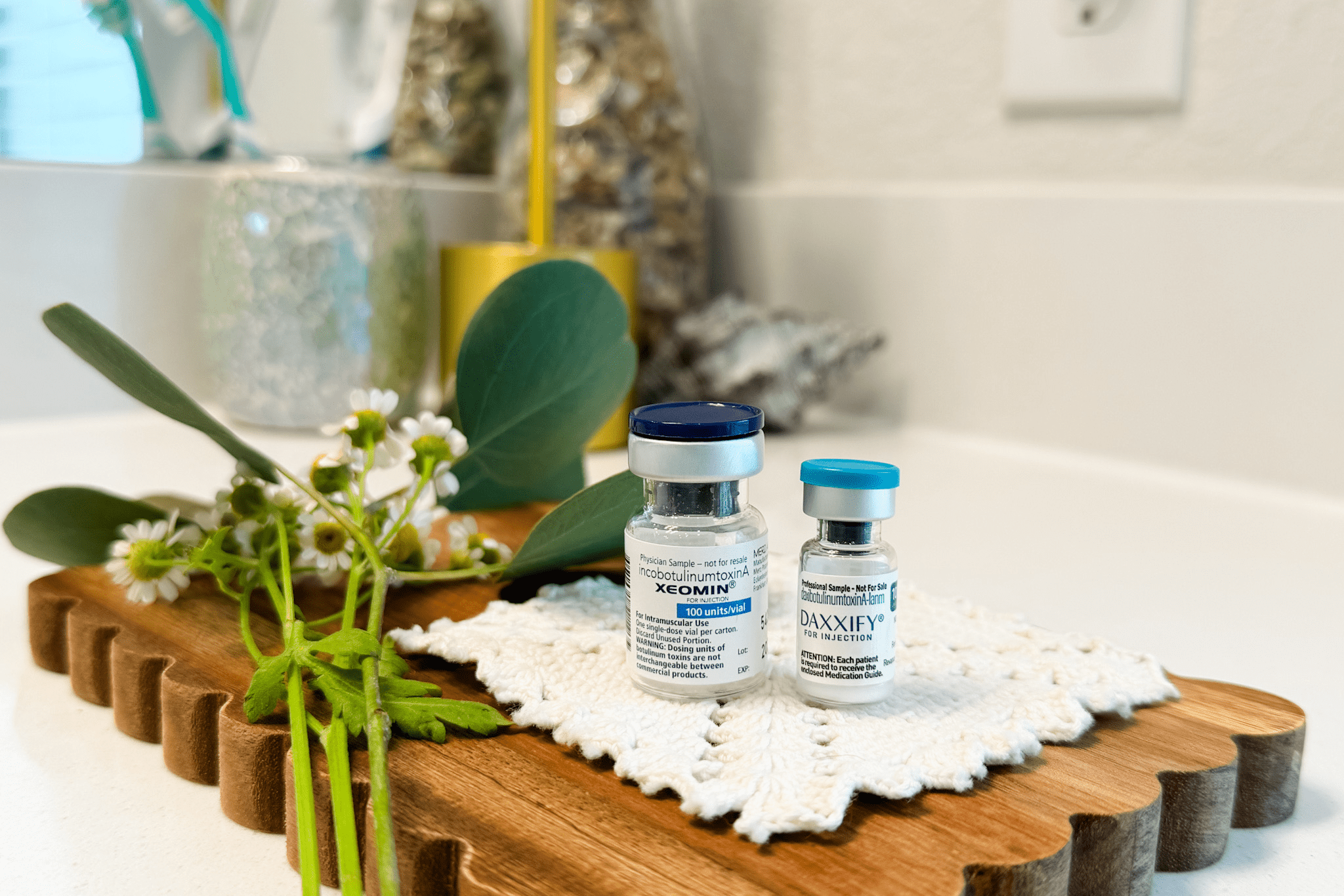Vaccine vials on wooden tray with flowers.