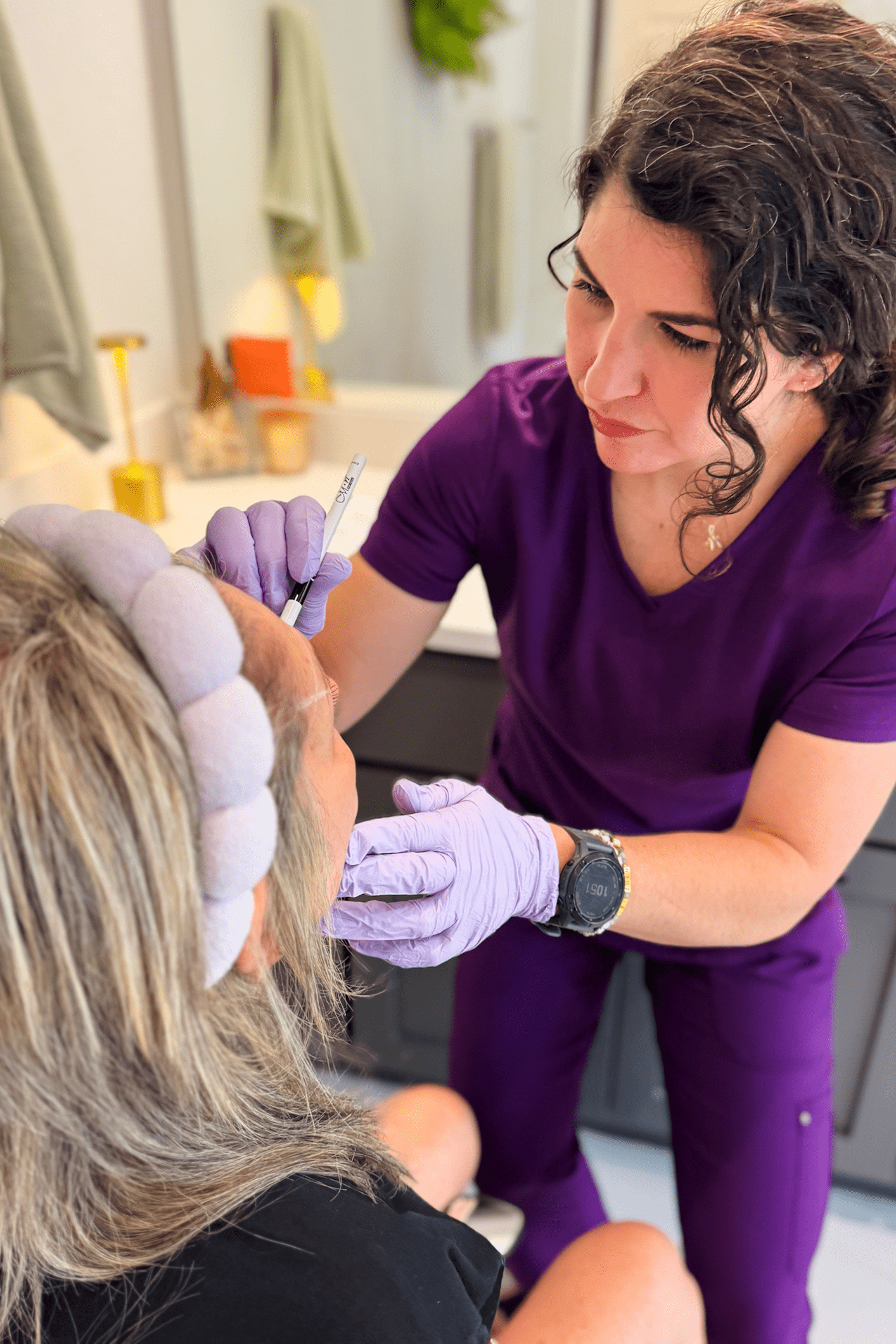 Woman administering facial injection to another woman.