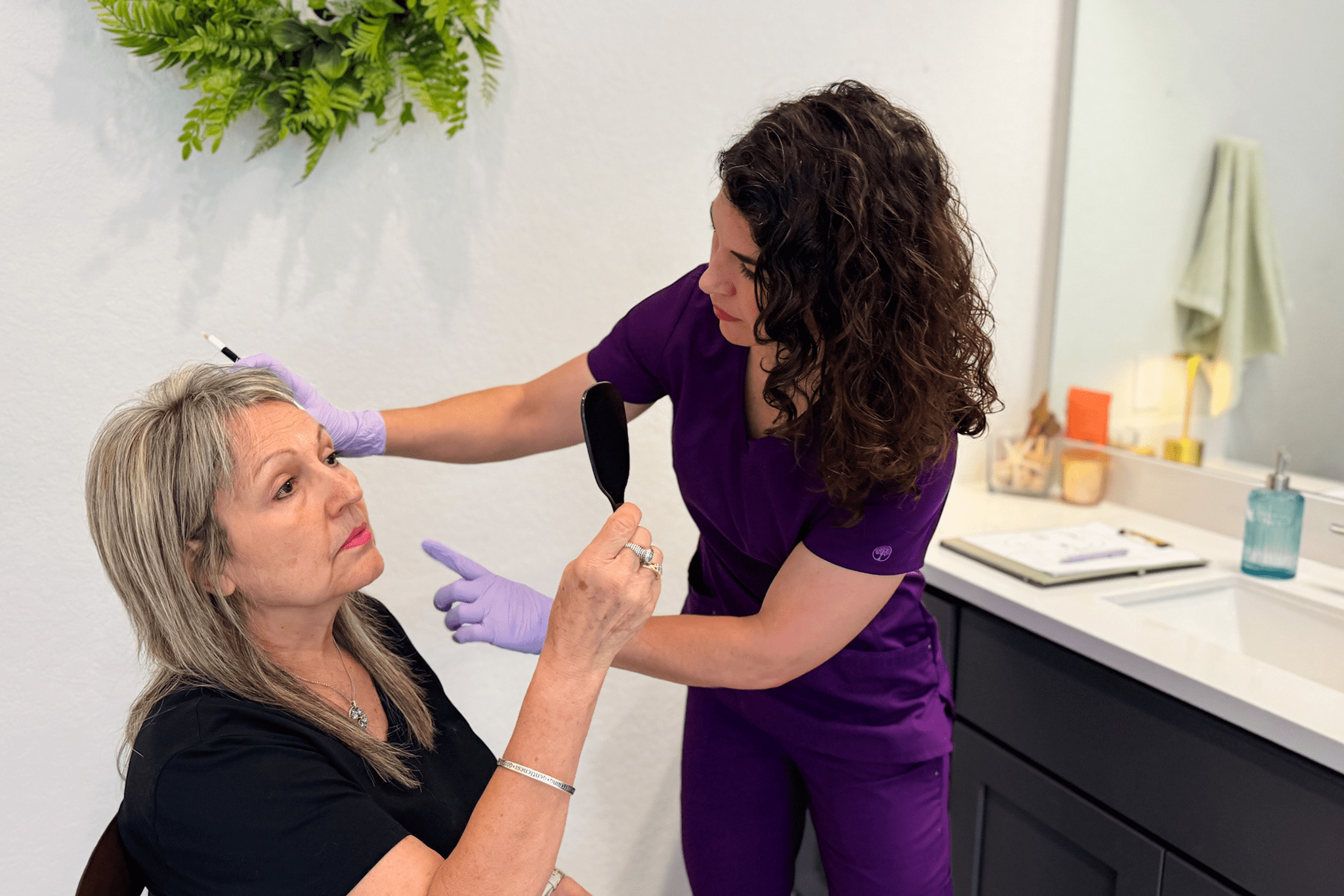 Woman receiving facial assessment in clinic.